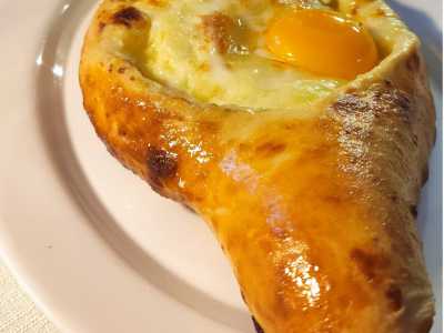 ...che propone piatti come il khachapuri: una focaccia ripiena, fatta con farina e yogurt, con all'interno vari tipi di formaggio fresco o stagionato, uova ed erbe. � disponibile anche nella variante con un uovo a tegamino sopra